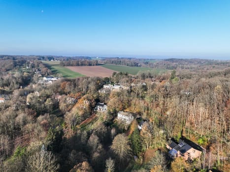 Aerial view of houses surrounded by forest and farmland in the country side area of Walloon, Belgium, Europe