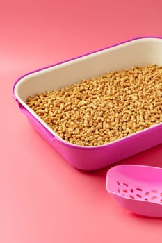 Pet litter box with bio filler on pink background close up