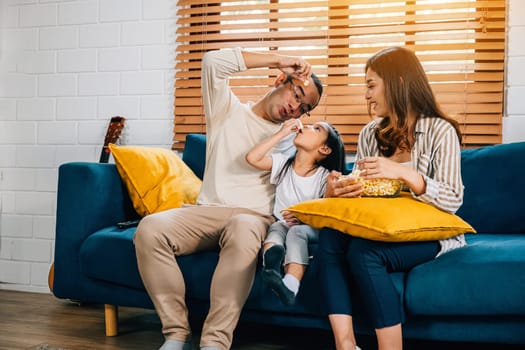 In their cozy house happy family with popcorn watches TV on sofa. father mother daughter and sibling radiate happiness epitomizing togetherness and relaxation during their quality time.