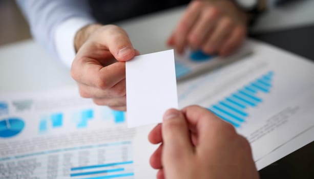 Male arm in suit give blank calling card to visitor closeup. White collar colleagues company name exchange job interview sale clerk id executive or ceo finance support formal identity etiquette