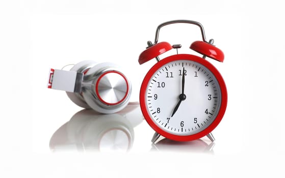 Red alarm clock with headphones isolated on white background shows seven minutes of the morning it's time to get up to wake up and have breakfast morning or evening jog to go to work music listen..