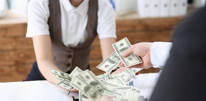 Businessman and business woman counting cash on the table at the office with hands very many dollars salary for the near future