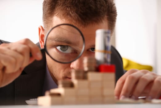 Businessman holds in hand black lens looks with an eye at tower of coins glass portrait closeup. Searches online best schedule 404 page not found concept.