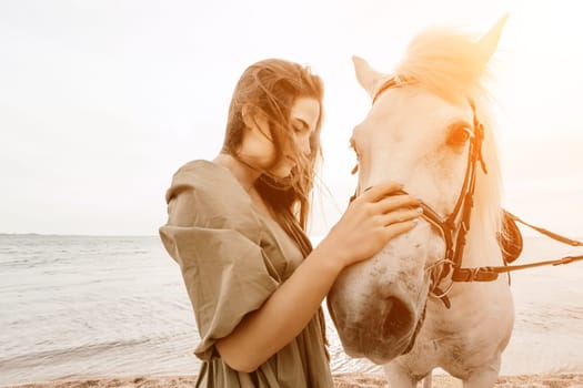 A woman in a dress stands next to a white horse on a beach, with the blue sky and sea in the background