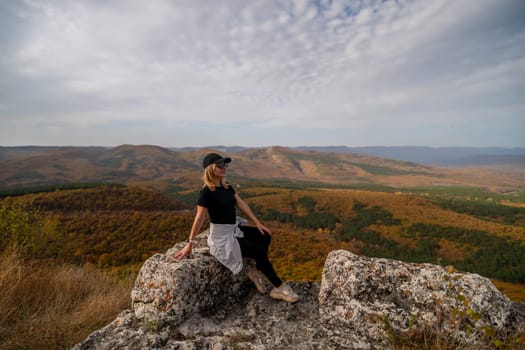 woman on mountain peak looking in beautiful mountain valley in autumn. Landscape with sporty young woman, blu sky in fall. Hiking. Nature.