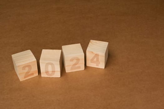 Wooden cube blocks with 2024 text on brown background. Start new year and business vision concept.