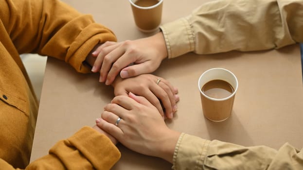 Married couple holding hands on date in cafe. Love, relationship, togetherness and lifestyle concept.