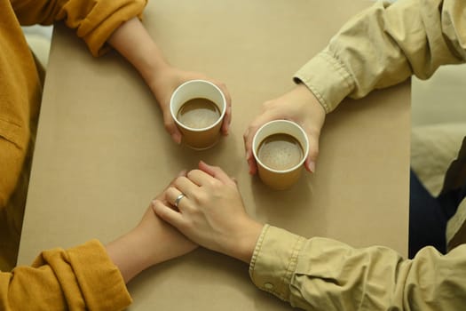 Loving young couple holding hands on table with coffee cups. Love, relationship and lifestyle concept.