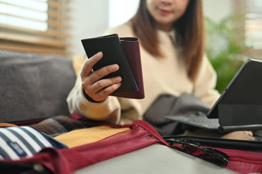 Woman holding passport and making hotel reservation on digital tablet. Travel and vacation concept.