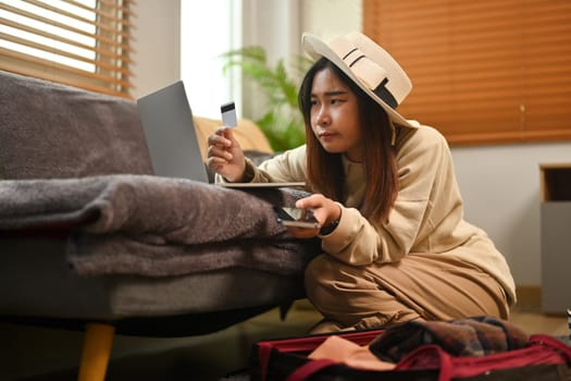 Young woman holding credit card and making hotel reservation on digital tablet.