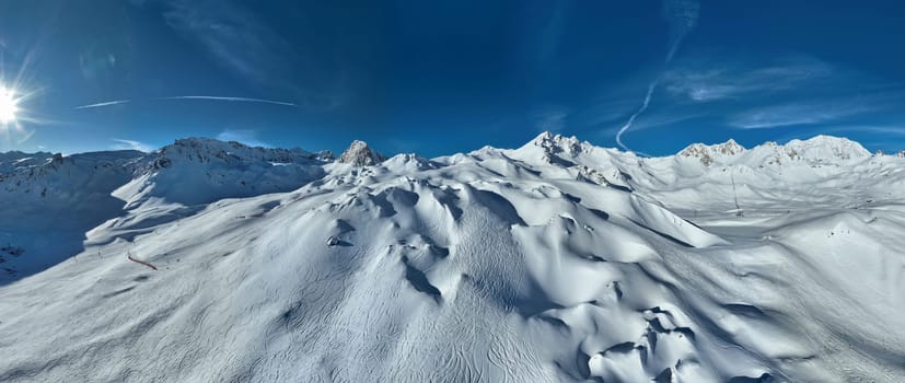 Winter drone shot of ski pistes and slopes covered with fresh powder snow in Tignes in Valdisere France. Alps aerial panoramic view on a beautiful sunny day ski lift snowboarding and skiing in resort