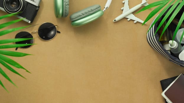 Top view of travel accessories with retro camera films, sunglasses headphone and passport on brown background.