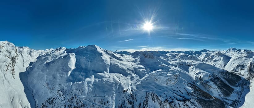 Winter drone shot of ski pistes and slopes covered with fresh powder snow in Tignes in Valdisere France. Alps aerial panoramic view on a beautiful sunny day ski lift snowboarding and skiing in resort