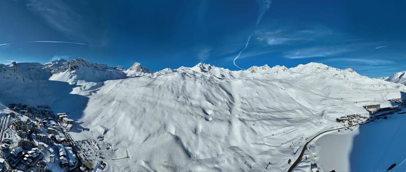 Winter drone shot of ski pistes and slopes covered with fresh powder snow in Tignes in Valdisere France. Alps aerial panoramic view on a beautiful sunny day ski lift snowboarding and skiing in resort