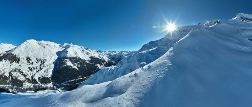 Winter drone shot of ski pistes and slopes covered with fresh powder snow in Tignes in Valdisere France. Alps aerial panoramic view on a beautiful sunny day ski lift snowboarding and skiing in resort