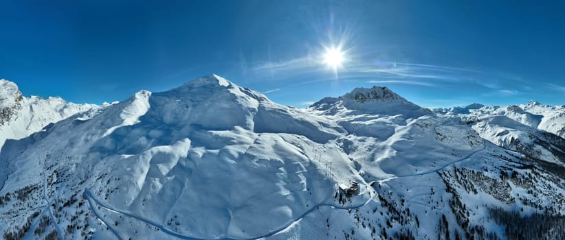 Winter drone shot of ski pistes and slopes covered with fresh powder snow in Tignes in Valdisere France. Alps aerial panoramic view on a beautiful sunny day ski lift snowboarding and skiing in resort