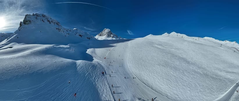 Winter drone shot of ski pistes and slopes covered with fresh powder snow in Tignes in Valdisere France. Alps aerial panoramic view on a beautiful sunny day ski lift snowboarding and skiing in resort