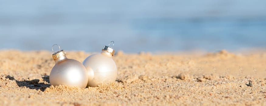 celebrating Christmas in hot countries. Christmas decorations bauble ball on sandy beach with sea background. copy space