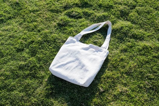 Mockup shopper handbag on green grass background. Top view copy space shopping eco reusable bag.