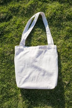 Mockup shopper handbag on green grass background. Top view copy space shopping eco reusable bag.