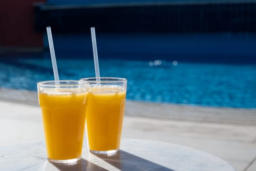 Refreshing cocktails near swimming pool, close up, copy space