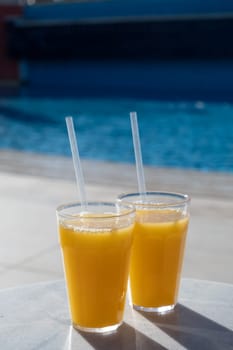 Refreshing cocktails near swimming pool, close up, copy space