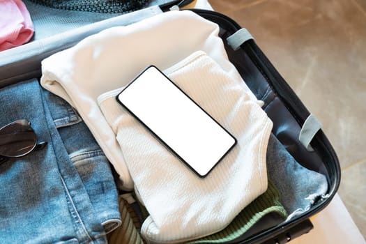 Travel concept. opened packed suitcase on bed in hotel room, smartphone screen mockup