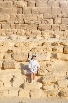 mature adult woman traveler wearing light colour clothing, facing the Pyramids of Gyza