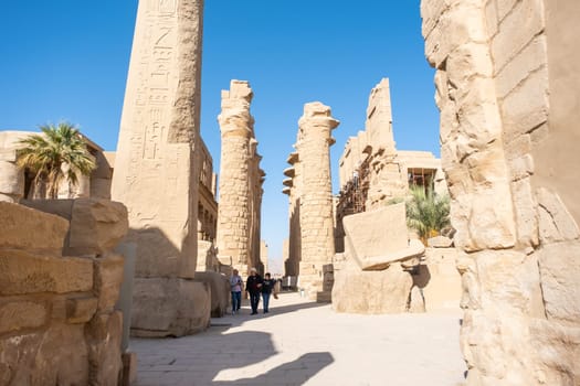 mature adult woman traveler explores the ruins of the ancient Karnak temple in the city of Luxor in Egypt. Great row of columns with carved hieroglyph