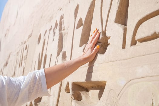 mature adult woman traveler explores the ruins of the ancient Karnak temple in the city of Luxor in Egypt. Great row of columns with carved hieroglyph