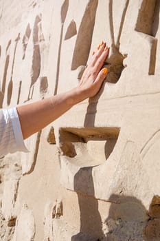 mature adult woman traveler explores the ruins of the ancient Karnak temple in the city of Luxor in Egypt. Great row of columns with carved hieroglyph