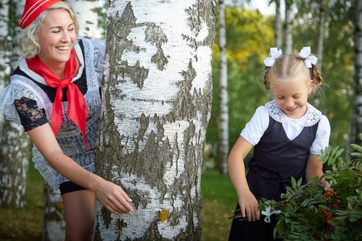 Young and adult schoolgirl on September 1, mother and daughter having fun and joy. Generations of schoolchildren of USSR and Russia. Female pioneer in red tie and October girl in modern uniform