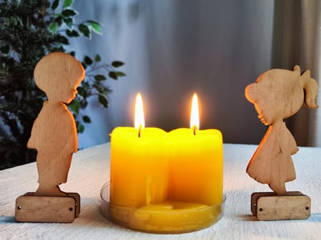 Wooden toys of boy and girl with yellow candles. Couple in love on Valentine's Day. Celebration of love and friendship. Card, background