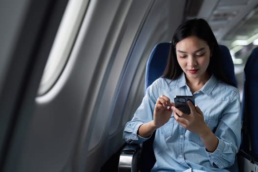 Asian people female person onboard, airplane window, using mobile while on the plane.