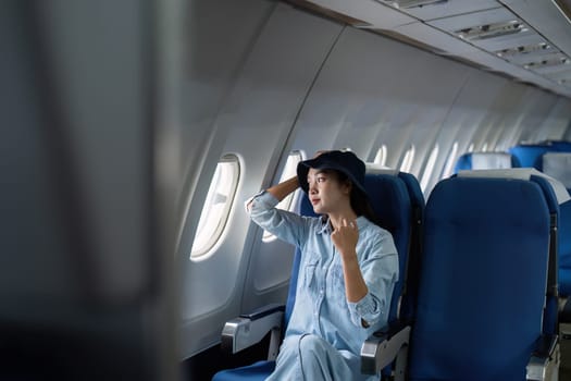 Asian people female person onboard, airplane window, looking at window while on the plane.