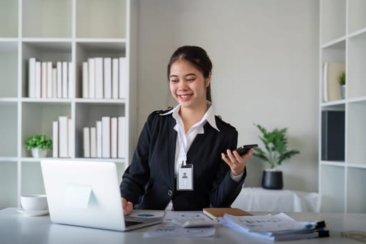 Charming Asian business woman sitting working on laptop in office.