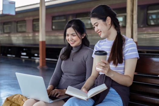 Woman traveler with backpack using laptop to planning vacation on holiday relaxation at the train station.