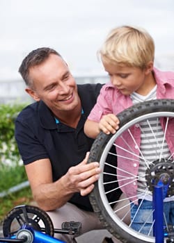 Bicycle, wheel or repair with father and son outdoor in neighborhood for learning or child development. Family, street and fixing with man parent teaching young boy tyre maintenance for cycling.