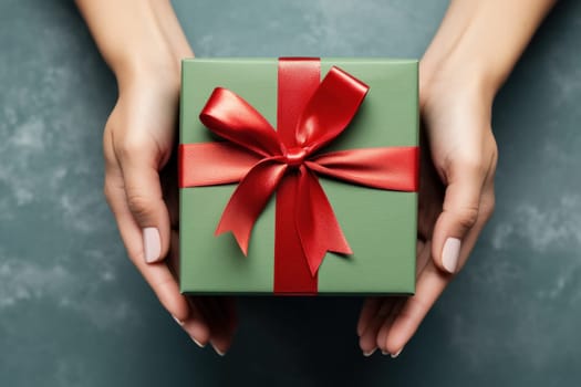 Hands holding dark green gift box and red ribbon top view, Christmas concept. Generative AI.