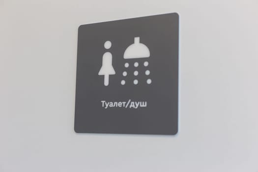 The pointer of the shower and toilet on a gray background, with an inscription in Russian (Toilet / shower), on a light wall