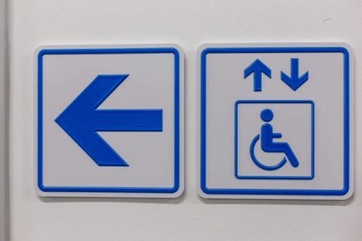 A blue arrow and elevator access signs disabled person on the wall.