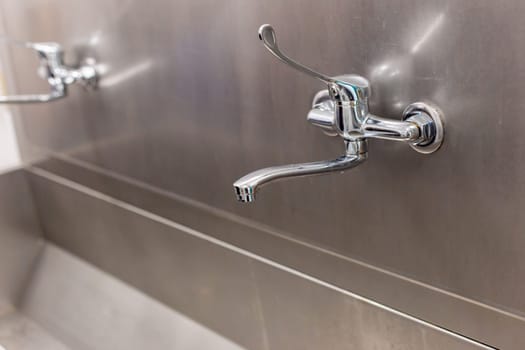 Close-up of a chrome Industrial-style public water Two taps in the surgery department at the hospital