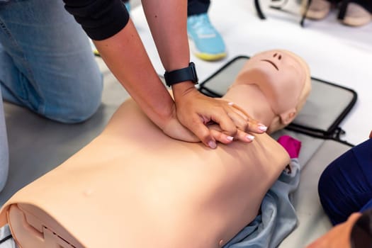 Close-up of hands performing CPR on a training manikin during a first aid class.