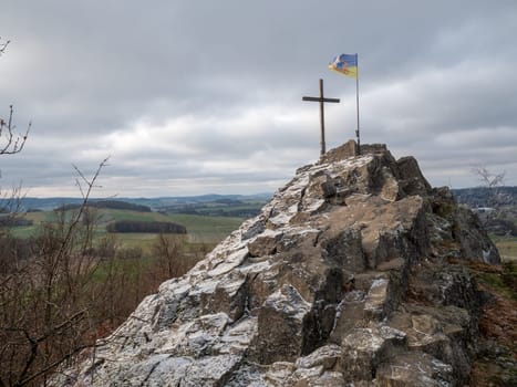 Oberlausitz flag  and cross on Goethekopf rock between Spitzkunnersdorf and Leutersdorf in Germany. Freeze winter weather with cloudy sky.