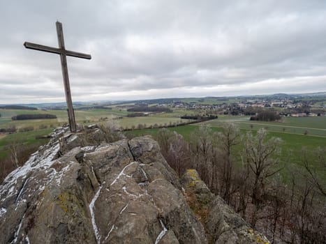 Wooden cross on top of Goethekopf mountain between Spitzkunnersdorf and Leutersdorf in Germany. Freeze winter weather with cloudy sky.
