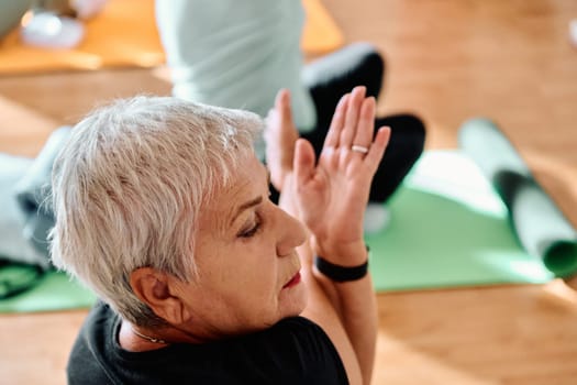 In a sunlit space, a senior woman gracefully practices rejuvenating yoga, focusing on neck, back, and leg stretches, embodying serenity and well-being.