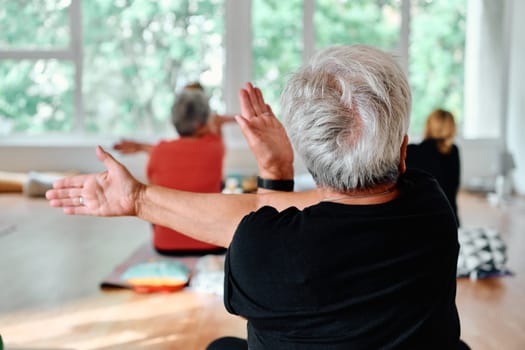 In a sunlit space, a senior woman gracefully practices rejuvenating yoga, focusing on neck, back, and leg stretches, embodying serenity and well-being.