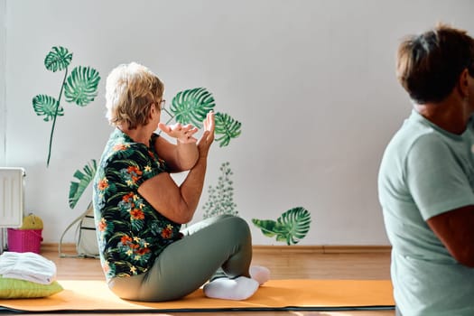 A group of senior women engage in various yoga exercises, including neck, back, and leg stretches, under the guidance of a trainer in a sunlit space, promoting well-being and harmony.