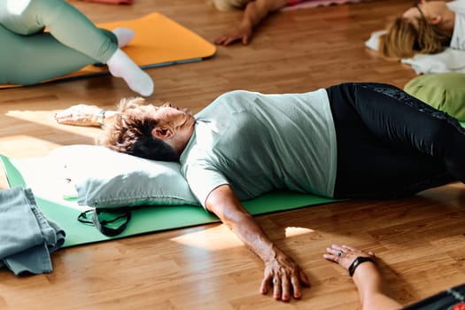 In a sunlit space, a senior woman gracefully practices rejuvenating yoga, focusing on neck, back, and leg stretches, embodying serenity and well-being.