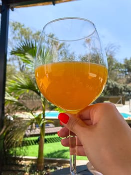 Woman with red nail manicure holding a glass of orange juice in their hand, palms on the background. High quality photo